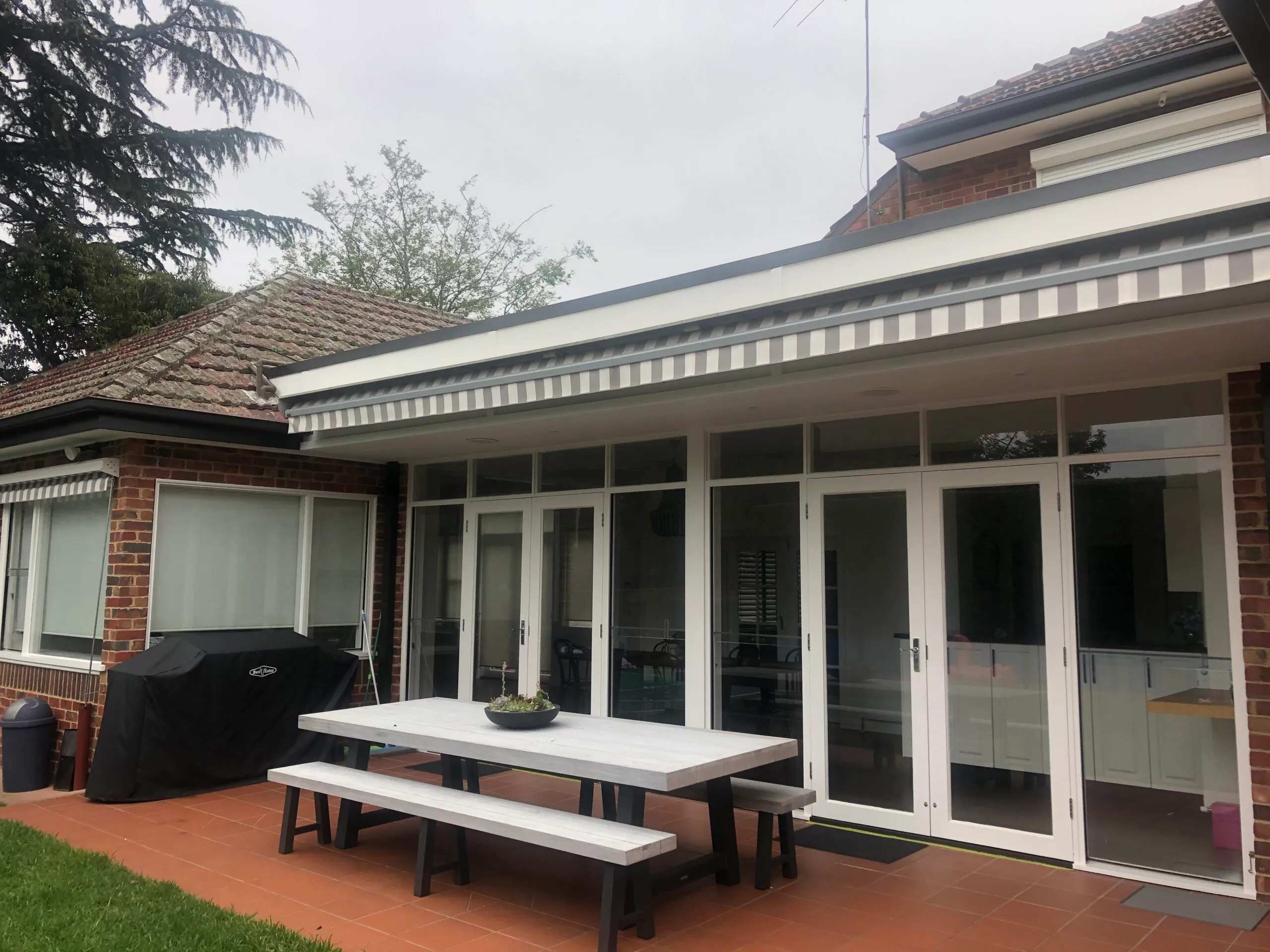 Rear of a Melbourne home with crisp white painted bifold doors, window frames and eaves against original brickwork