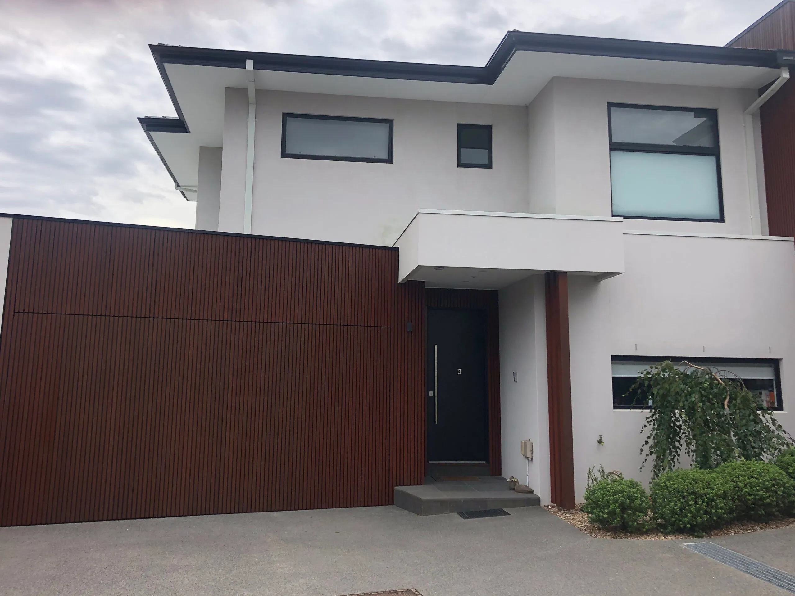 Contemporary Melbourne townhouse with white render, dark trim and stained timber cladding